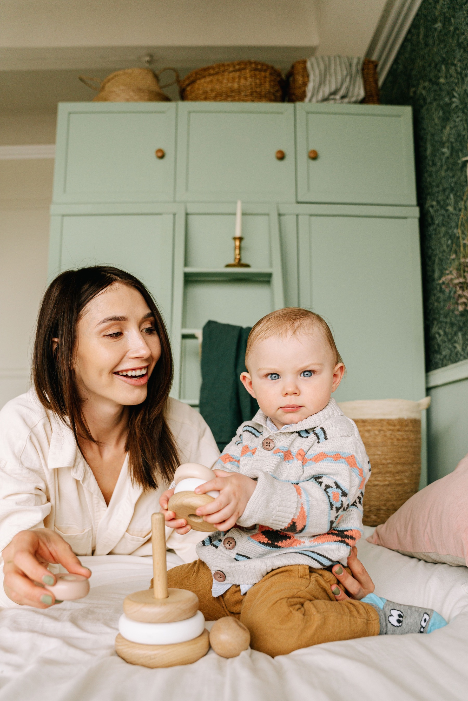 A baby exploring wooden toys with an attentive caregiver