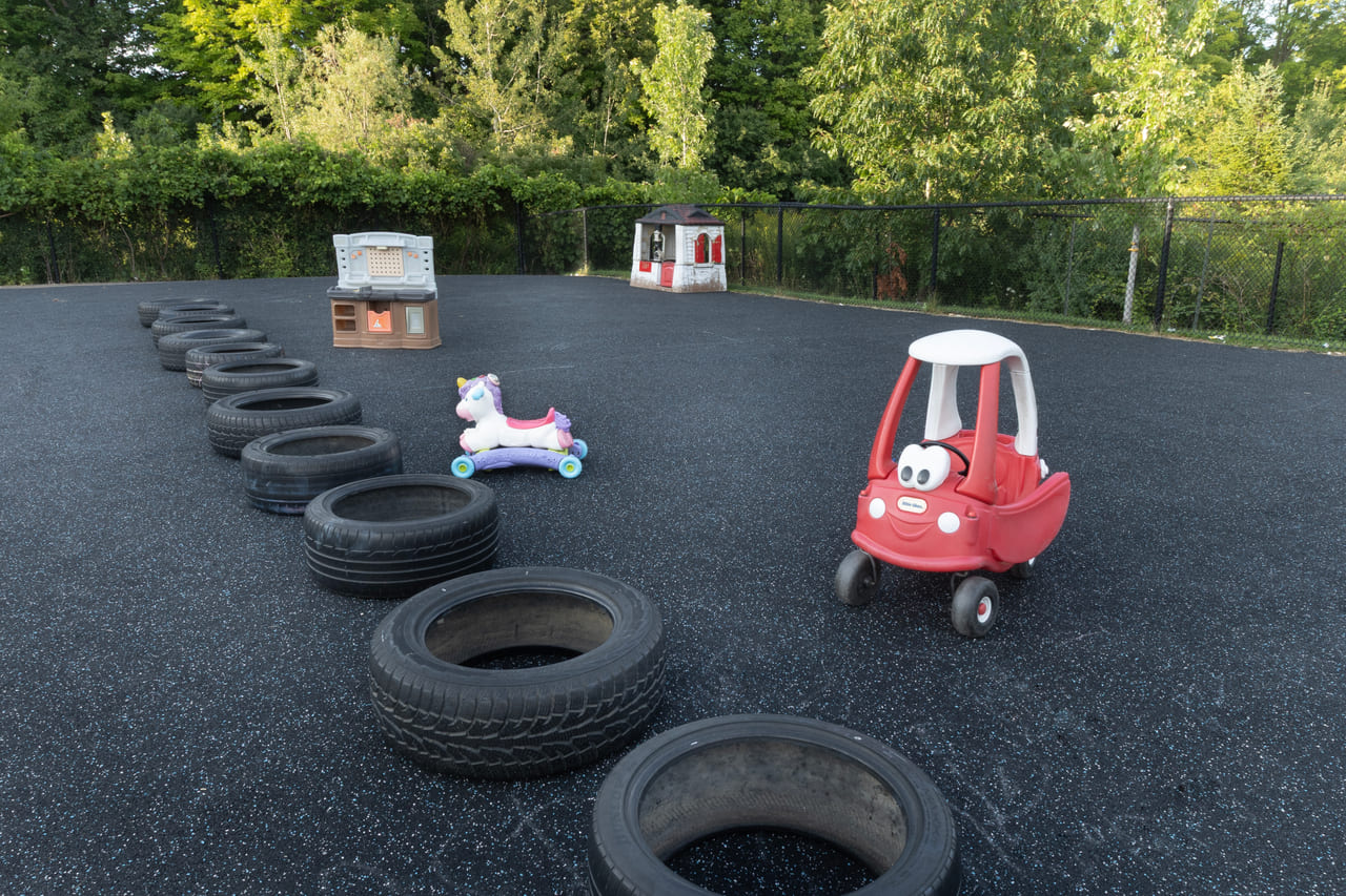 The outdoor play yard with a tyre course and ride-on cars for active toddler play