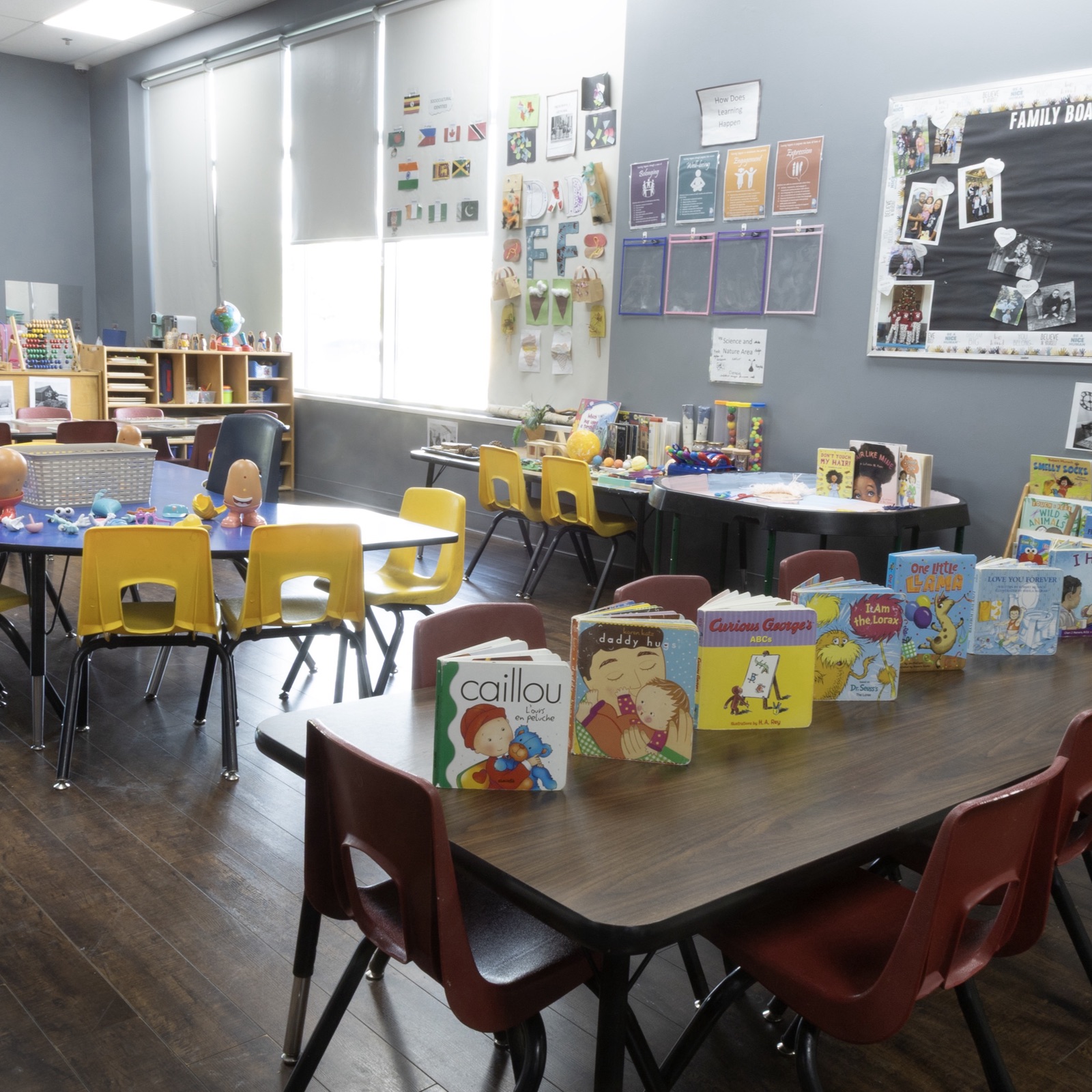 A bright Tender Years classroom with child-size tables, picture books and family displays