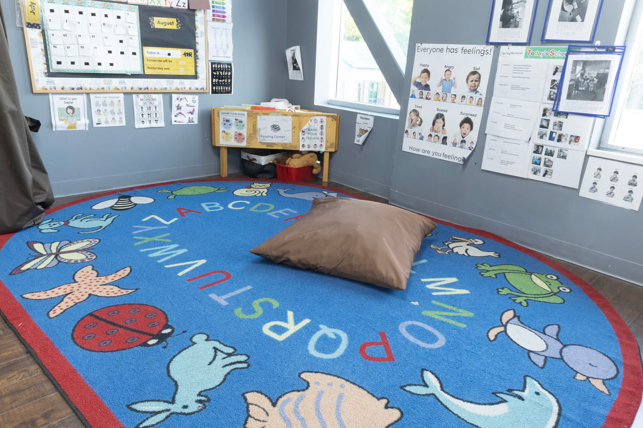 A cosy corner with an alphabet rug and a floor cushion