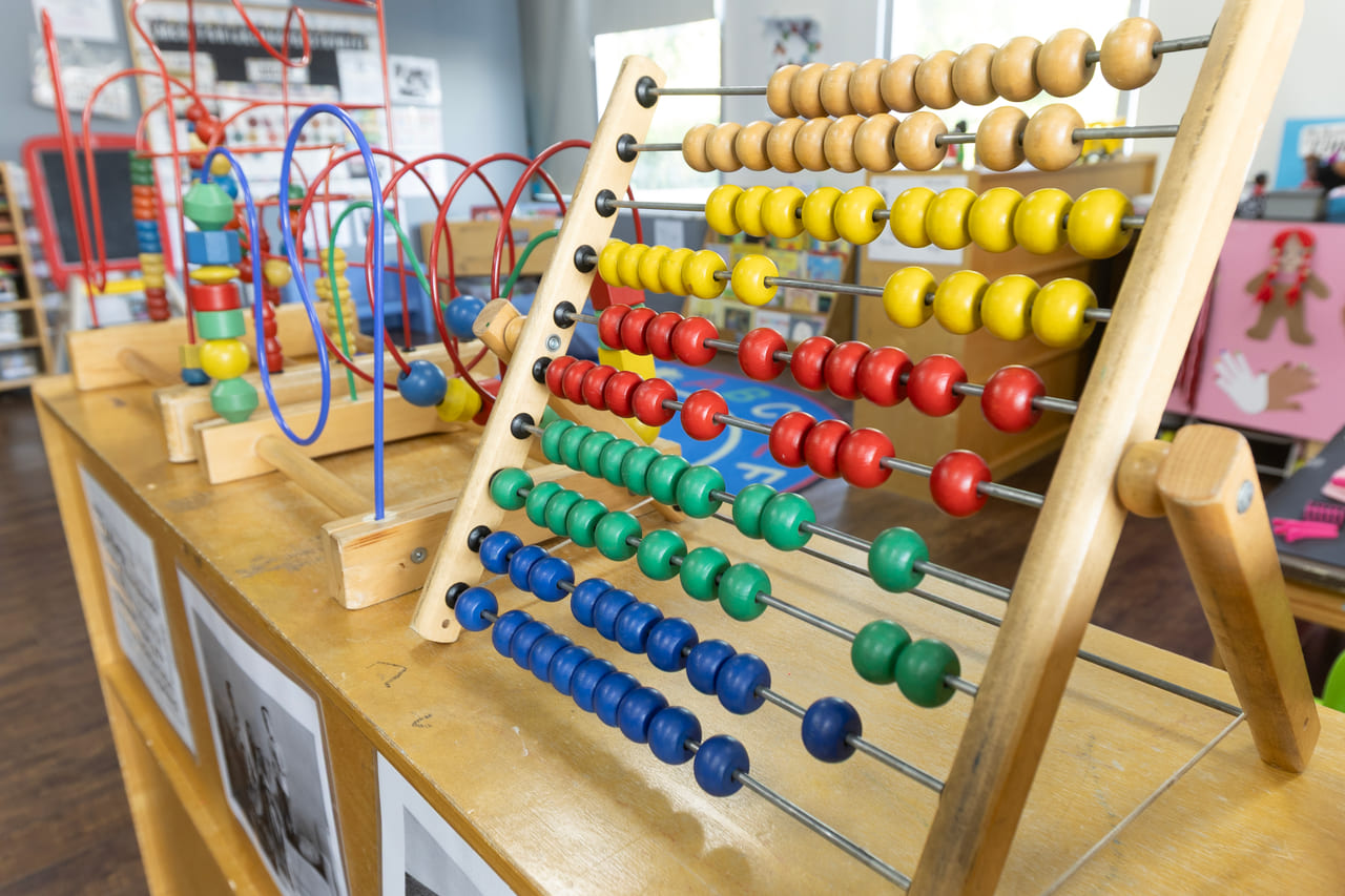 A wooden abacus and bead maze set out for counting and fine-motor play