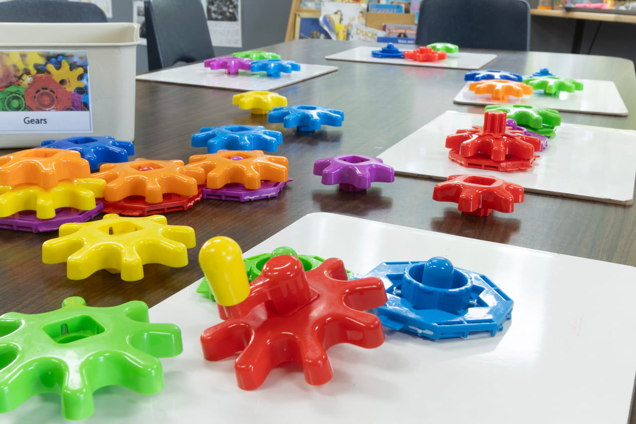 Interlocking plastic gears in bright colours on a classroom table
