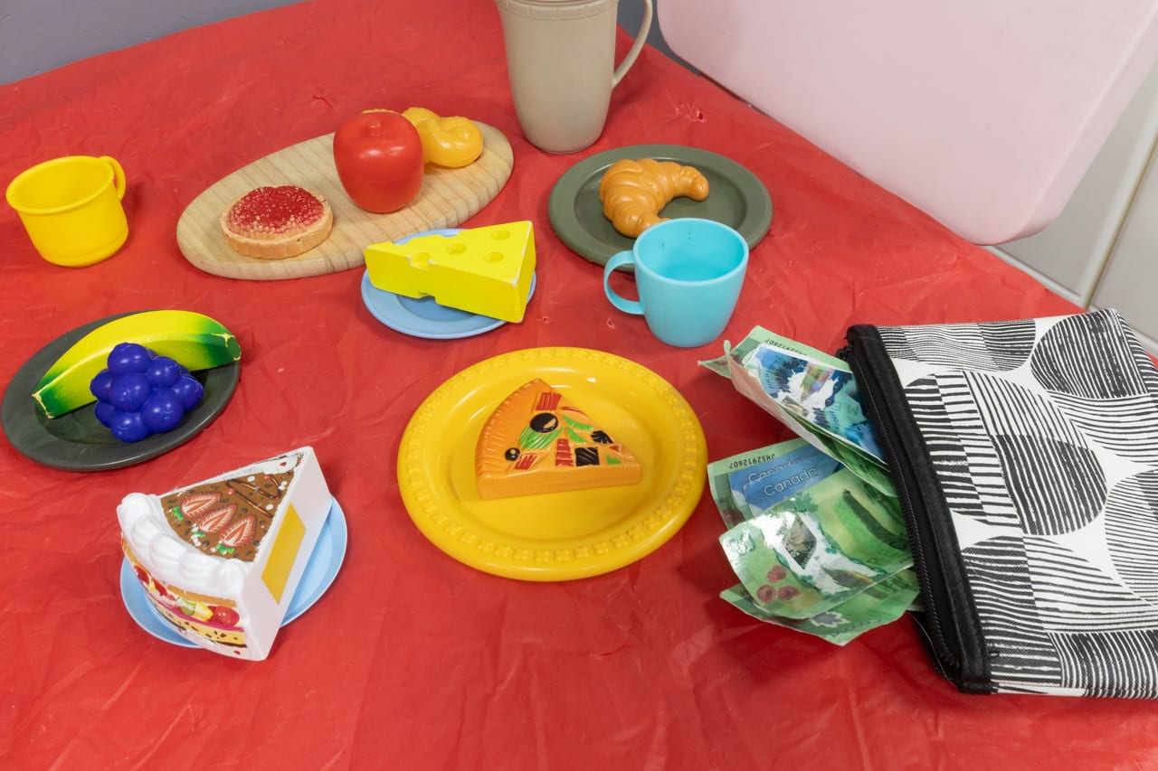 A pretend picnic with toy food and colourful dishes on a red tablecloth