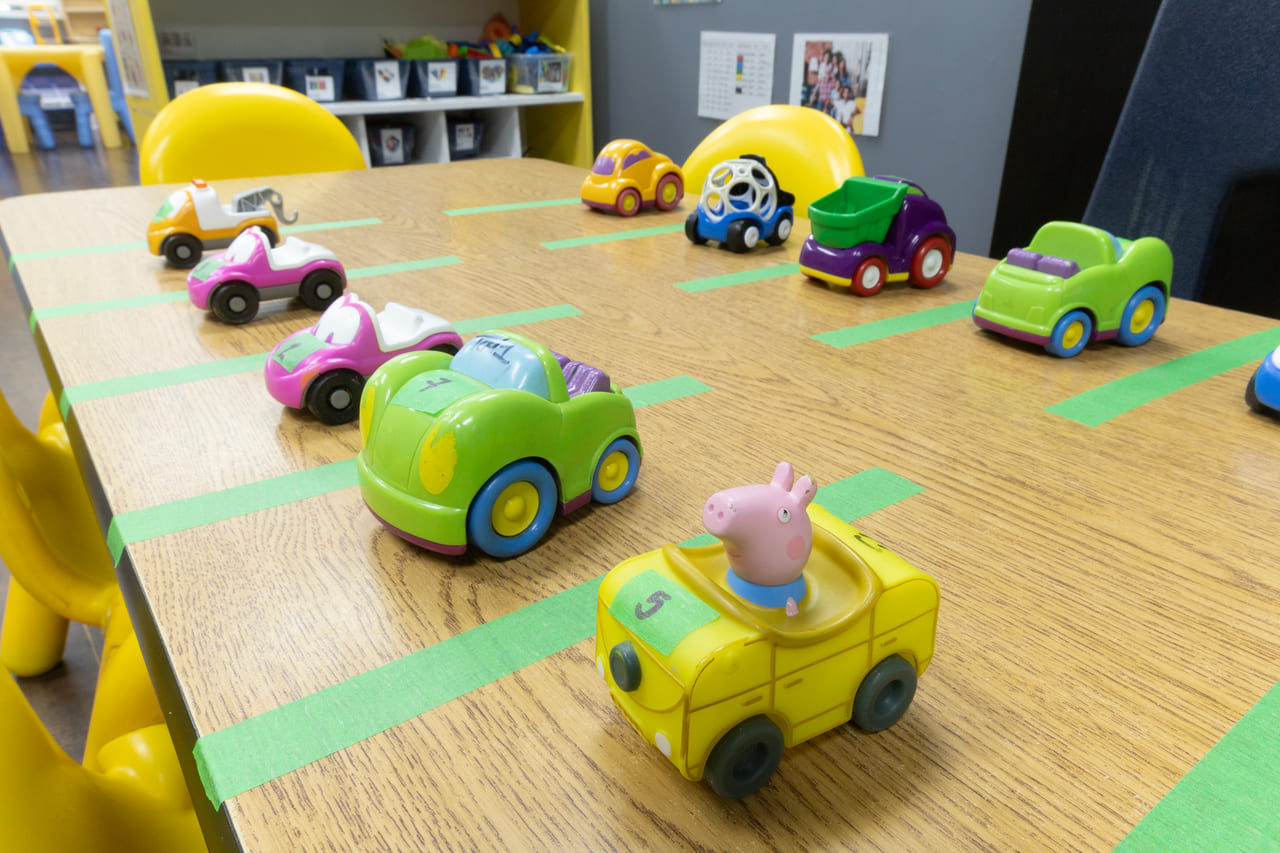 Toy cars and a bus on a taped-out road running across a classroom table