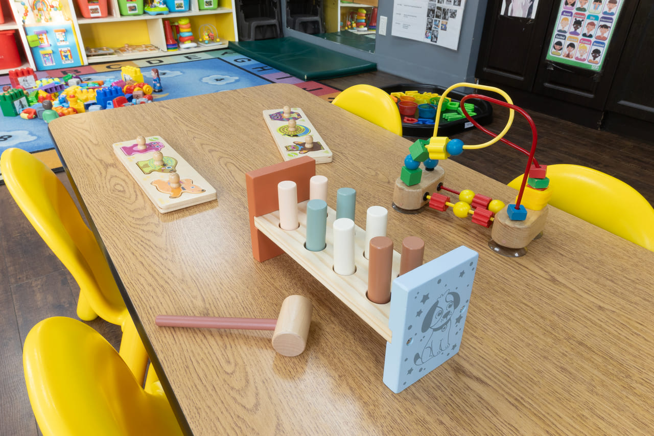 Wooden stacking toys and a bead maze set out on a low table