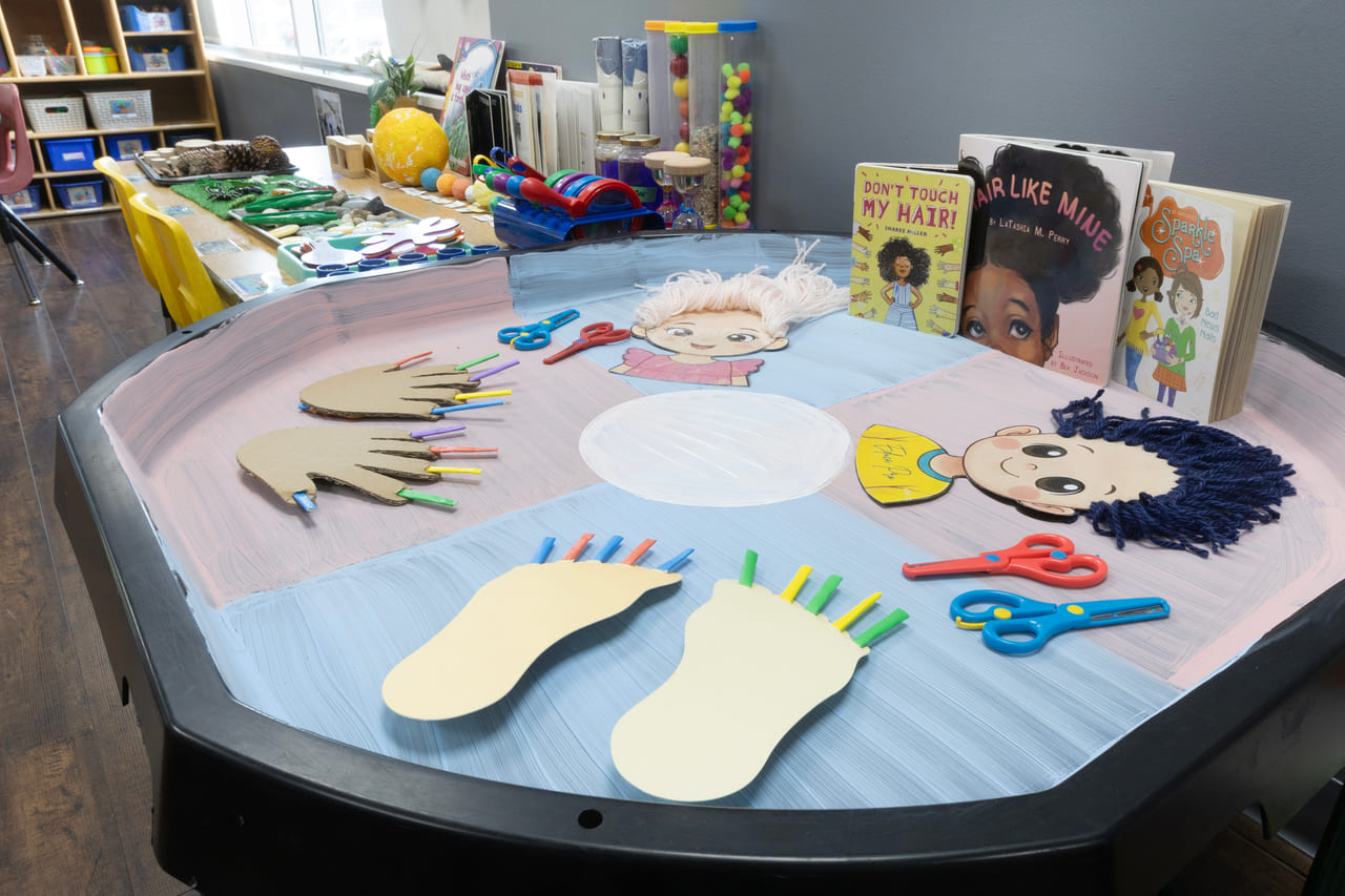An art table set with paper hands, feet and collage materials