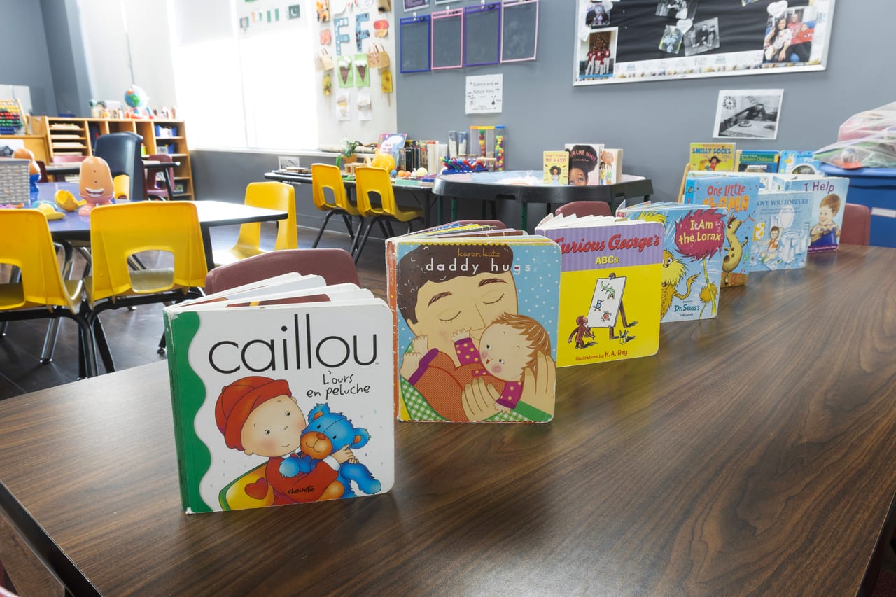 Board books standing along a classroom table beside a bright window