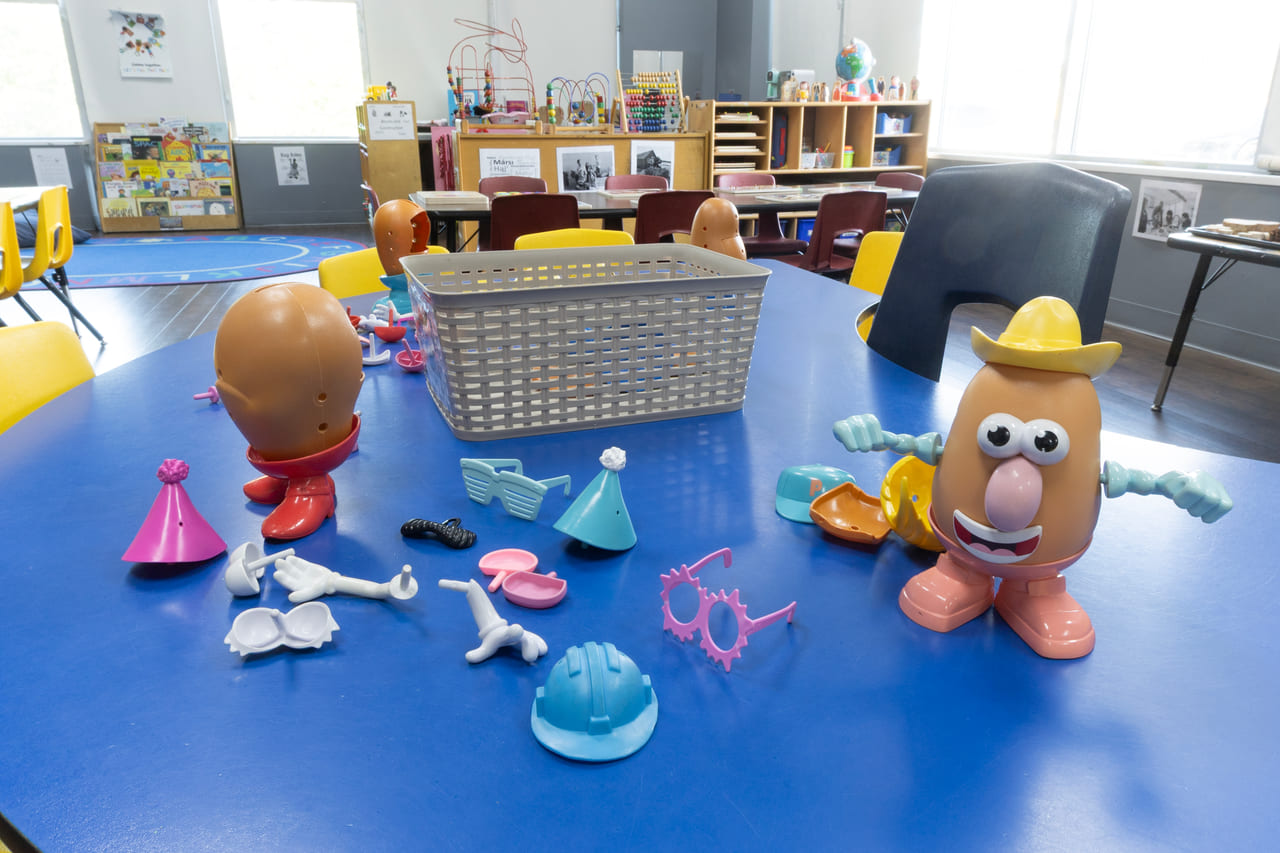 A tuff tray of play figures, tools and shape pieces set out on a table